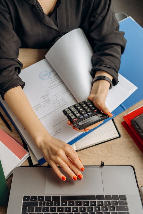 woman typing and holding a calculator